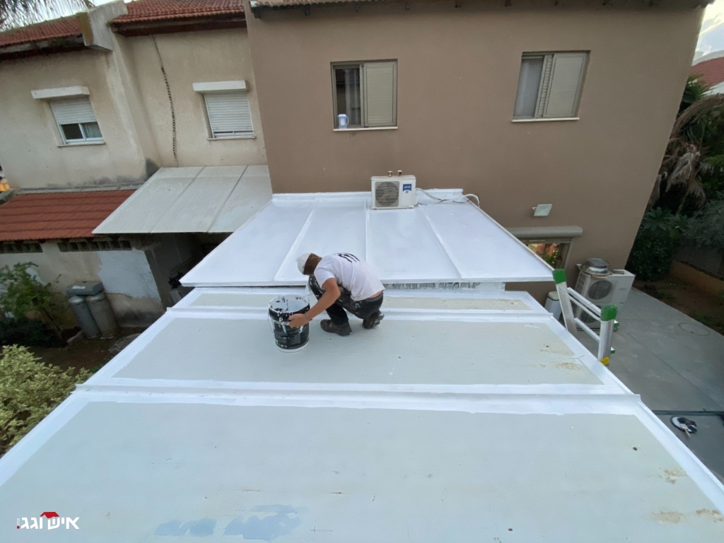 איש צוות מבצע עבודת מריחה של חומר איטום על גג שטוח